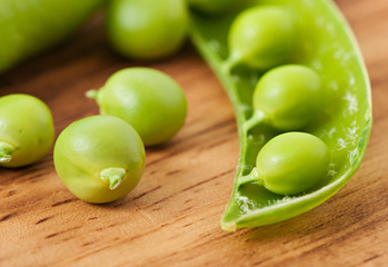 Sweet green peas on an old wooden background.