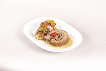 Slice roasted pork, served with potatoes and decorated with herbs, placed on white plate, light background, isolated