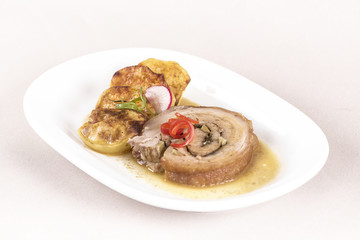 Slice roasted pork, served with potatoes and decorated with herbs, placed on white plate, light background, isolated
