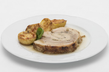 Slice roasted pork, served with potatoes and decorated with herbs, placed on white plate, light background, isolated