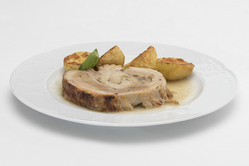 Slice roasted pork, served with potatoes and decorated with herbs, placed on white plate, light background, isolated