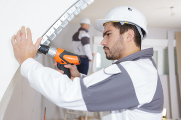 young man drilling wall indoors