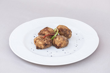 Fried pane sweetbreads, decorated with herbs, isolated on light background, white plate