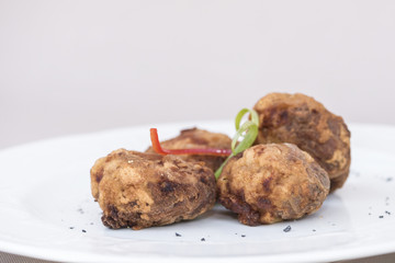 Fried pane sweetbreads, decorated with herbs, isolated on light background, white plate