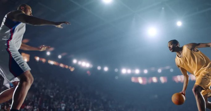 4K footage in slow motion basketball player dribbling in front of rival player. The action takes place in 3d made basketball arena full of spectators. All players wear unbranded basketball uniform.