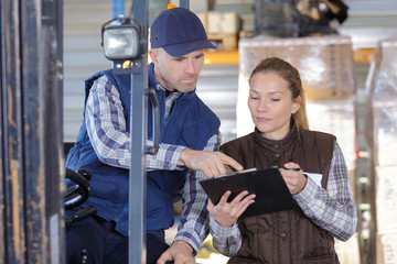 forklift driver talking with his manager in a large warehouse