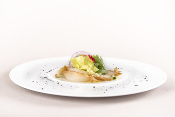 Fresh appetizer with smoked white fish, rucola, baby spinach and green salad, with red eatable flowers, placed on white plate, light background, isolated