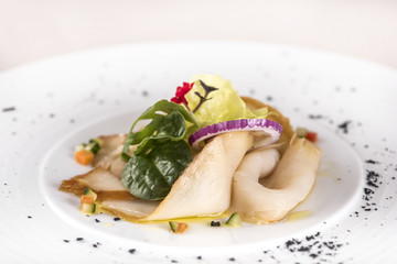 Fresh appetizer with smoked white fish, rucola, baby spinach and green salad, with red eatable flowers, placed on white plate, light background, isolated