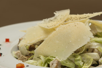 Grilled meat salad, served with parmesan and rucola, isolated on light background, white plate