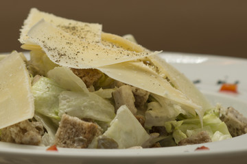 Grilled meat salad, served with parmesan and rucola, isolated on light background, white plate
