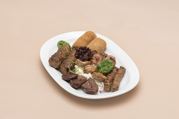 Traditional Romanian food plateau, with sausages, grilled meat, sweetbreads, potatoes, pickles, mustard, polenta, mushrooms, mici and vegetable salad, decorated with herbs, isolated on light backgroun