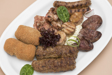 Traditional Romanian food plateau, with sausages, grilled meat, sweetbreads, potatoes, pickles, mustard, polenta, mushrooms, mici and vegetable salad, decorated with herbs, isolated on light backgroun