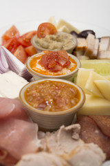 Traditional Romanian food plateau, containing different types of meat and cheese, tomatoes, onion, cucumber, olives and salads: “zacusca”, eggplant salad and beans salad, decorated with herbs, isolate