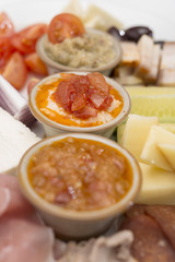 Traditional Romanian food plateau, containing different types of meat and cheese, tomatoes, onion, cucumber, olives and salads: “zacusca”, eggplant salad and beans salad, decorated with herbs, isolate