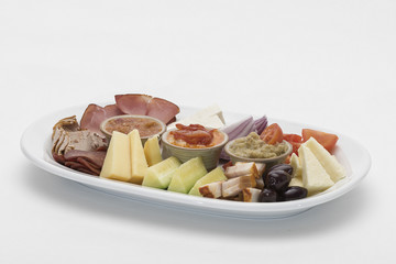Traditional Romanian food plateau, containing different types of meat and cheese, tomatoes, onion, cucumber, olives and salads: “zacusca”, eggplant salad and beans salad, decorated with herbs, isolate