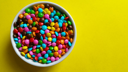 Colorful confetti in white pot on yellow background