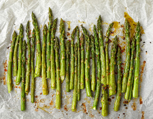 Grilled green asparagus on a white pepper on a white paper background, top view