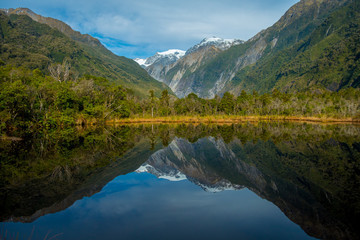 Small pond peters pond with reflection of mountain glacier Franz Josef Glacier in New Zealand