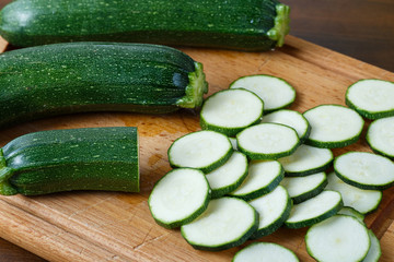 Fresh sliced zucchini on cutting board, on wooden background