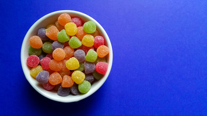 Sweet jujubes in white pot on blue background top view and space to write