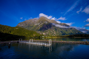 landscape of high mountain glacier at milford sound with a small pier in the lake, in south island in New Zealand