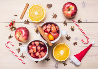 Fresh Christmas drink mulled wine, apple, orange, cinnamon and cloves, next spread ingredients, candy, decorations for the New Year top view