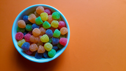 Sweet jujubes in white pot on orange background top view