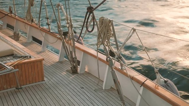 Wooden deck of ship standing at seashore outdoors. Small vessel is located near coastal wharf on splashing turquoise waters of Adriatic Sea on warm summer day. Boat of which upper part is made of
