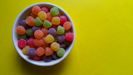 Sweet jujubes in white pot on yellow background top view