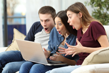 Amazed friends watching content on line in a computer