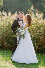 Portrait of the bride and groom in full growth at a wedding on nature in the spring at sunset