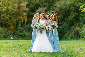 Obraz na płótnie Canvas Beautiful slim bride walks with friends in a blue dress at sunset