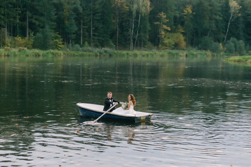 The groom skates the bride on a boat. Loving couple on a walk after the ceremony
