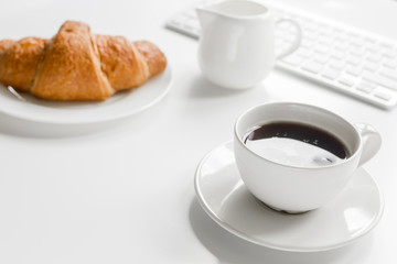 croissant and cup of coffee on office desk for business breakfast white background