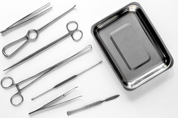 Surgical instruments and tools including scalpels, forceps and tweezers on white table top view mock up