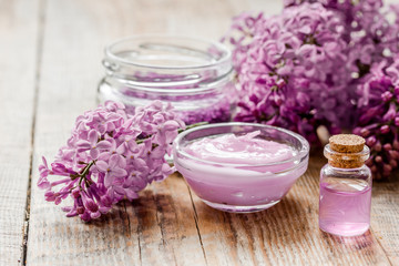 Fototapeta na wymiar take bath with lilac cosmetic set and blossom on wooden table background