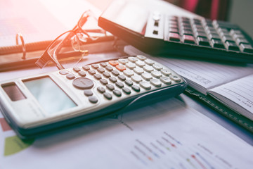 Calculator with business graphs and charts report on tabble, calculator on desk of financial planing. Financial abstract concepts.