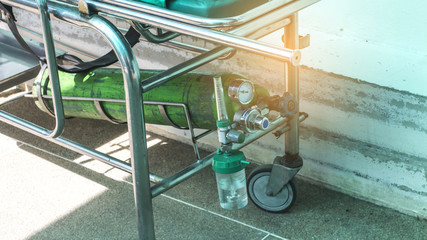 Oxygen cylinder on patient bed.