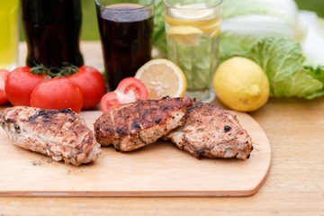 Сhicken breast grilled on a wooden Board. Chicken chili steak on the background with vegetables and black soda and lemonade, food photography