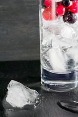 Glass of ice with berry gooseberries red black currants and water. Refreshing cocktail. Summer drink.