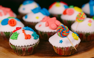 Baby cupcakes on the wooden background.
