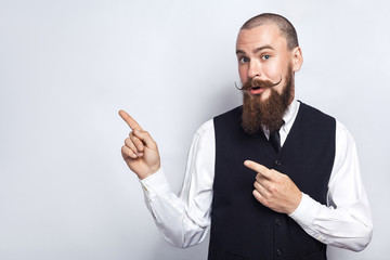 Handsome businessman with beard and handlebar mustache looking at camera, surprised and showing...