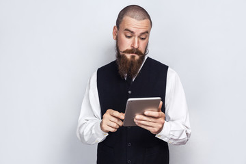 Handsome businessman with beard and handlebar mustache holding and using digital tablet. studio...
