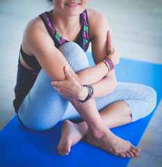 Fototapeta na wymiar Portrait of smiling yoga woman sitting at yoga mat after workout at yoga studio. Yoga. Woman.