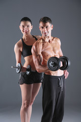 Fototapeta na wymiar Athletic man and woman with a dumbells. Personal fitness instruc