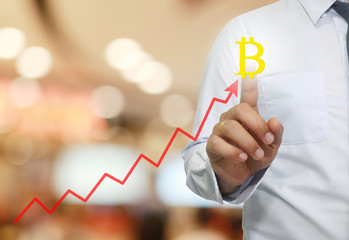 hand of businessman touche to symbol of bitcoin in business graph.