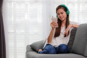 Fototapeta premium Young Asian girl listening to music with headphone and smarthphone