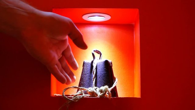 The hand touches the exhibition exhibit from a rare alloy under the light on a red background