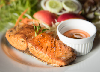 Fish steak with sauce and vegetable in background