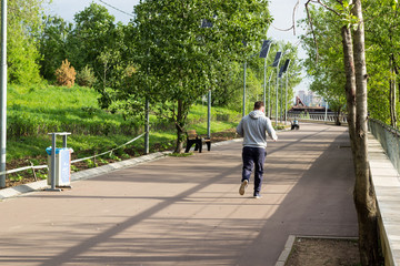 young guy jogging in city park at early morning